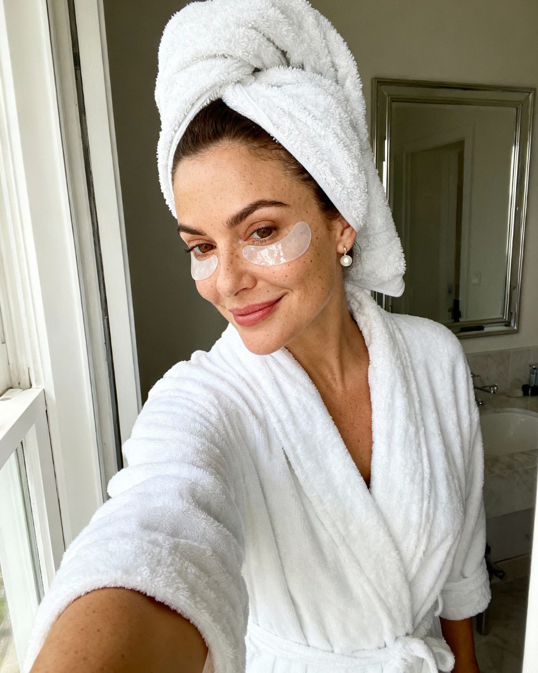 Frau im wei&szlig;en Bademantel mit Eye Pads