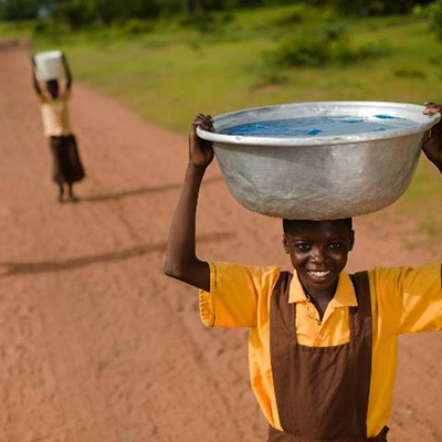 Projekt "Wasser für Schulen und Gemeinden" Junge trägt Wasserschüssel auf dem Kopf