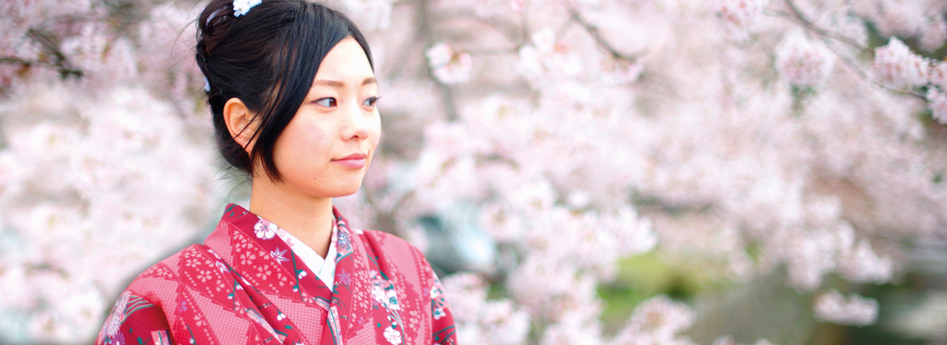 Entdecken Sie eine einzigartige Behandlung und exklusive Kabinenprodukte mit ausgewählten Wirkstoffen. Porträt junge Japanerin im Kimono vor Kirschblüten